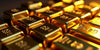 Photograph of stacked gold bars on a dark background.