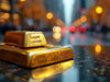 Gold bullion bar on reflective surface with blurred background.